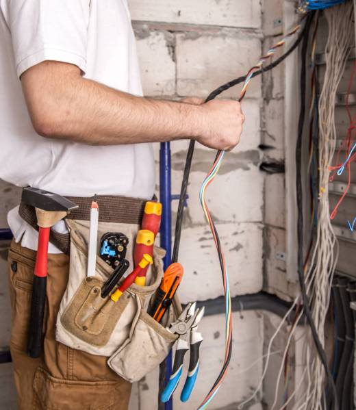 Electrician working near the Board with wires. Installation and connection of electrics. Professional with tools in hand.